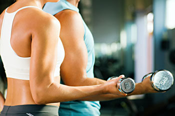 two people seen from the neck down using dumbbells to work their biceps