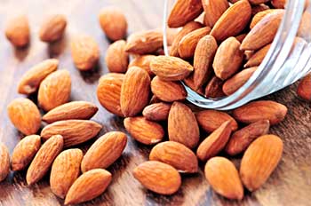 whole almonds spilling out of a glass bowl