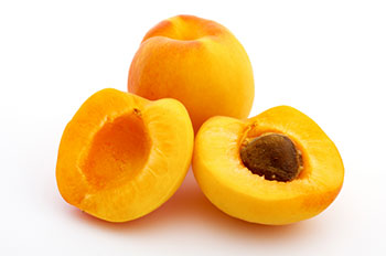 2 apricots - one is sliced in half to show the pit