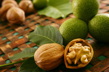several whole walnuts on a woven mat with one walnut split open to show the nut meat