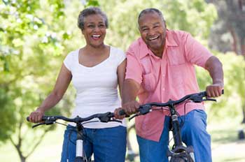 two African-American adults, both smiling, enjoying a bicycle ride