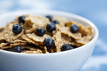A bowl of cereal garnished with blueberries. Children's cereals often contain HFCS.