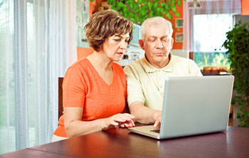 a man and a woman of middle age look together at a laptop