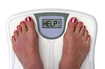 A woman's feet on a scale, which reads, 'help!'