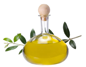 a glass bottle with a wooden stopper containing olive oil, flanked by an olive branch