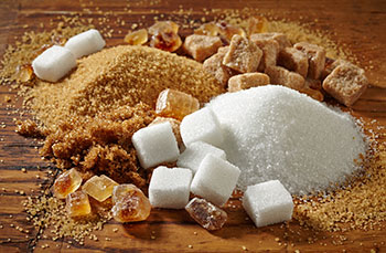 several types of raw and refined brown and white sugars poured in small piles