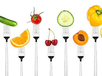 single bites of a variety of fruits and vegetables held up on forks