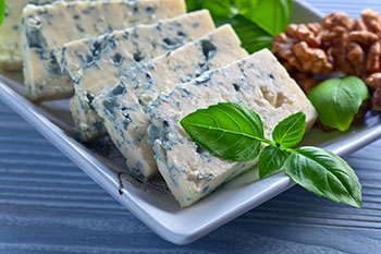 slices of gorgonzola, a type of blue cheese, on a plate with pecans and watercress garnish