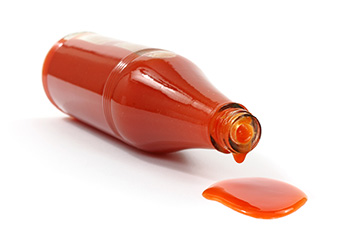 a bottle of hot sauce on its side with sauce spilling out of it