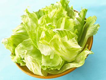 fresh, whole leaves of iceberg lettuce in a wooden bowl