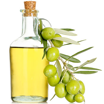 a glass bottle containing olive oil with a branch of fresh olives