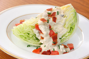 a wedge of iceberg lettuce topped with blue cheese dressing and bacon bits
