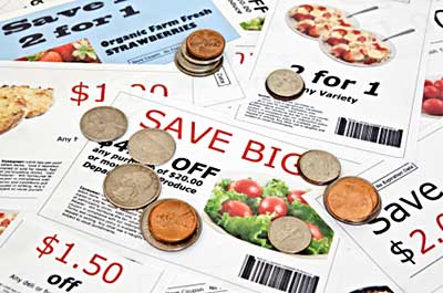 several store and manufacturer coupons in a scattered pile. Coins are littered over the pile