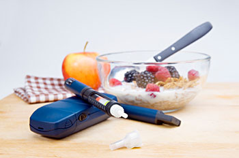 a glucose monitor, insulin syringe, and a bowl of cereal with milk
