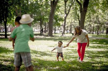 a family of four playing together in a wooded park setting