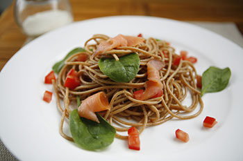 a bowl of whole grain pasta with spinach and tomatoes