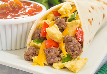 a breakfast burrito with sausage, eggs, cheese, and vegetables