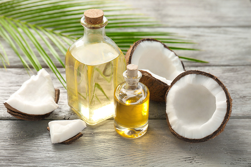 a cut-open coconut and glass containers of coconut oil