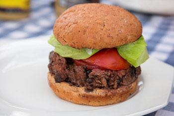 a hamburger made with beef and garnished with tomato, lettuce, and ketchup