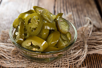 slices of pickled jalapenos in a small glass bowl