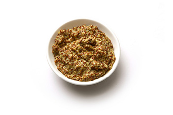 a bowl of prepared mustard containing mustard seeds.