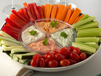 fresh sliced carrots, celery, bell peppers, and zucchini arranged on a platter surrounding small bowls of dip