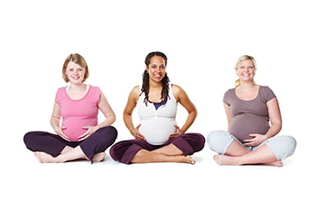3 pregnant women seated on the ground, cross-legged